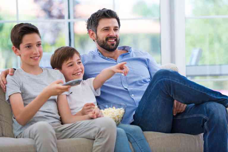 Father and sons watching tv at home